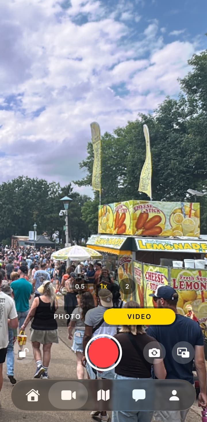 The hey vidi! capture screen framing a crowded state fair midway, with photo and video modes and a large shutter button